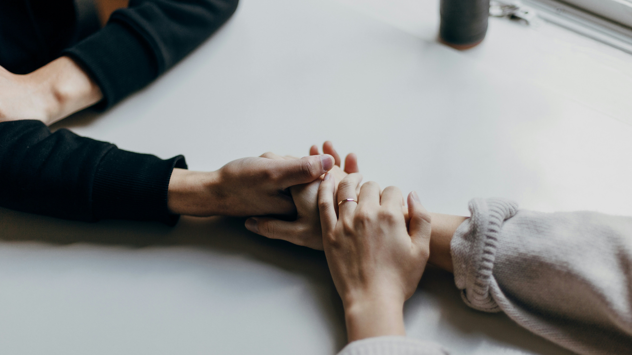 A man and woman holding hands on top of a contemporary white table.