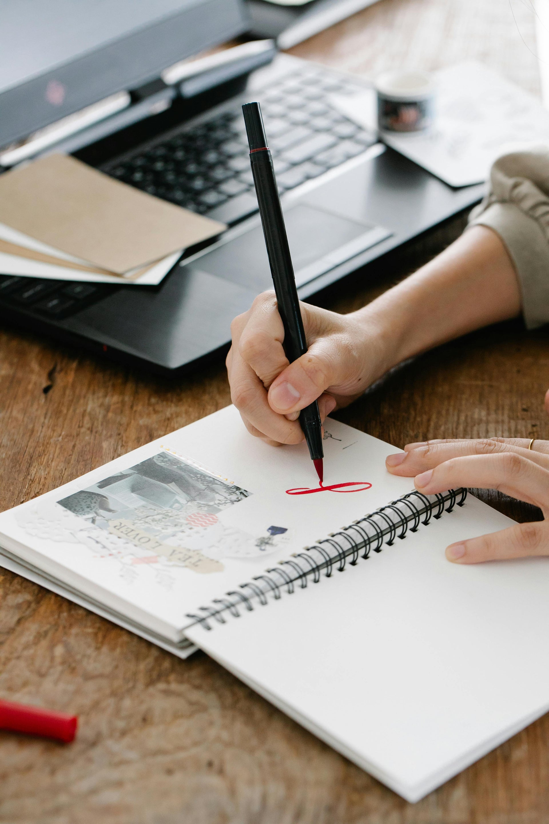 Person drawing in a notebook with a red marker.