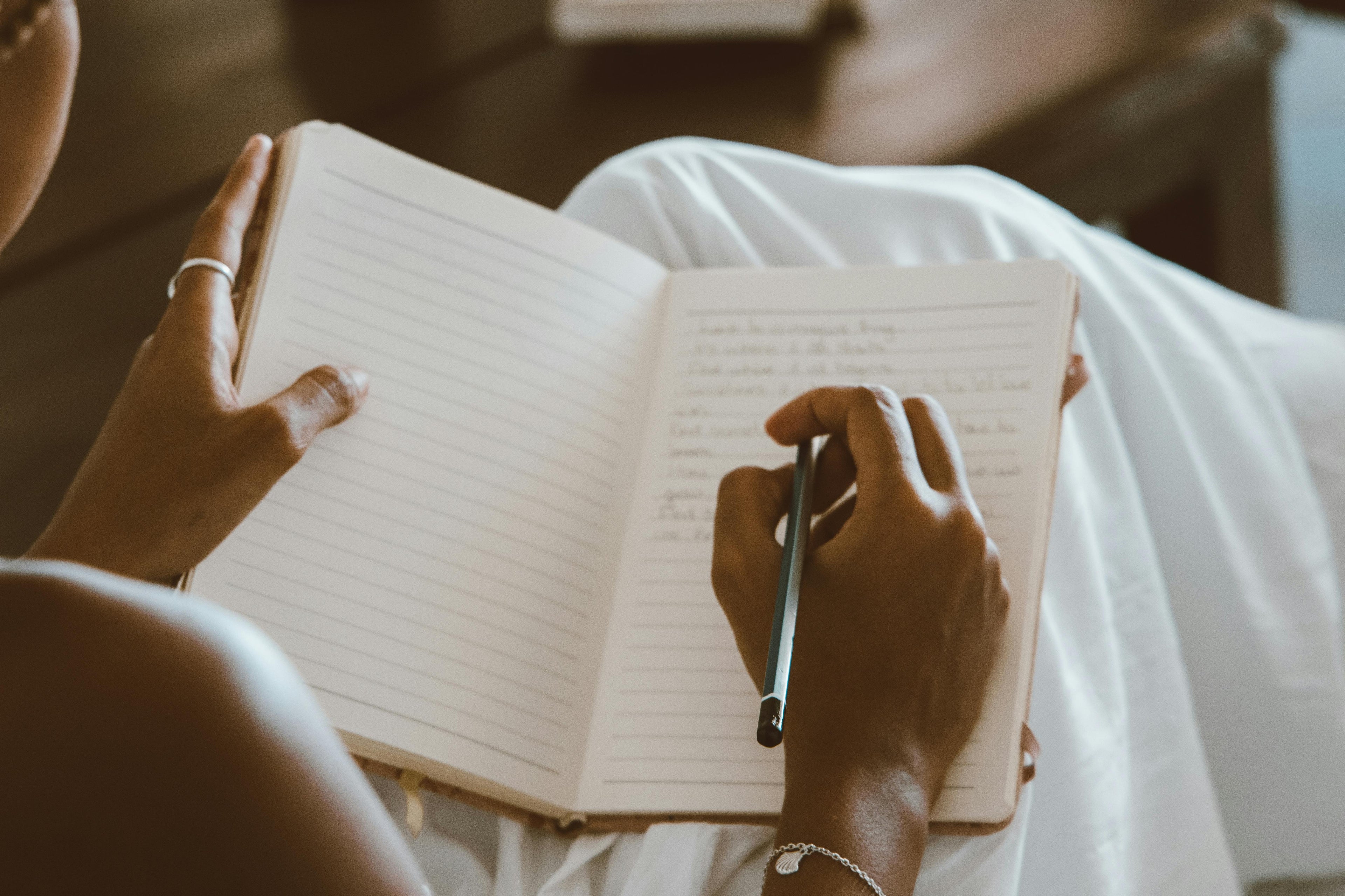 Person writing in a notebook with a pen.