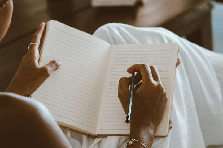Person writing in a notebook with a pen.